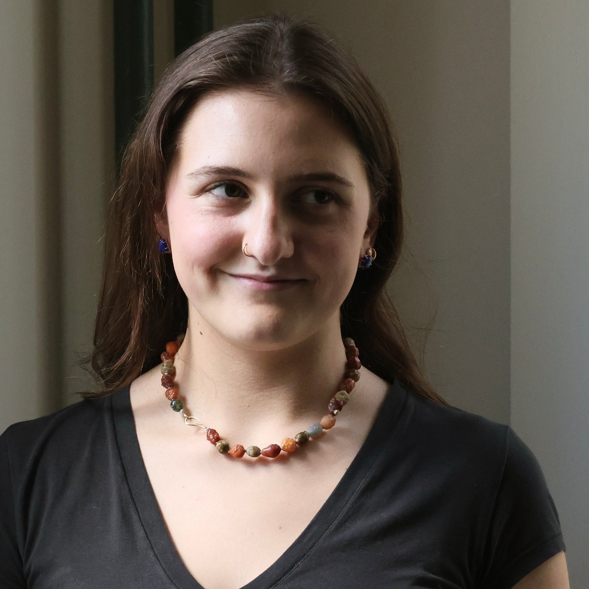 Woman wearing a beaded necklace against a neutral background