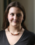 Woman wearing a beaded necklace against a neutral background