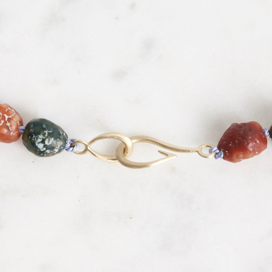 Close-up of a necklace with beads and a gold clasp on a white background