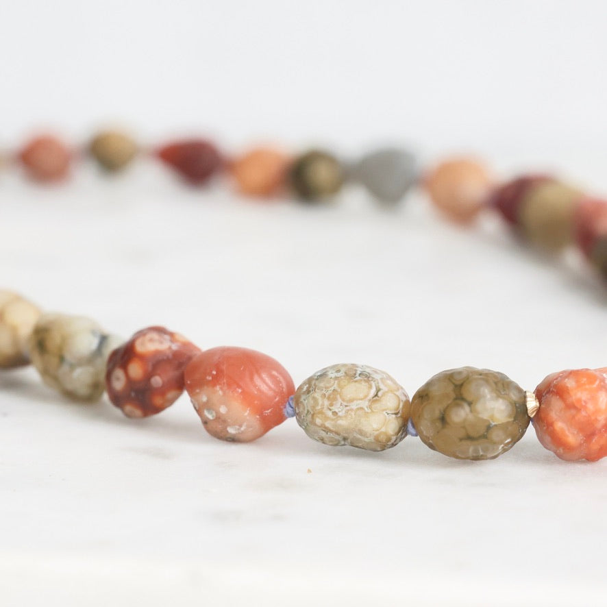 Close-up of a beaded necklace with multicolored beads on a white background