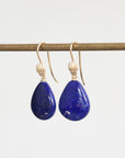 Bright blue lapis earrings hanging from bar with gold ear wires that have shell details 