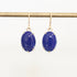 Pair of blue earrings on a gold rod against a white background