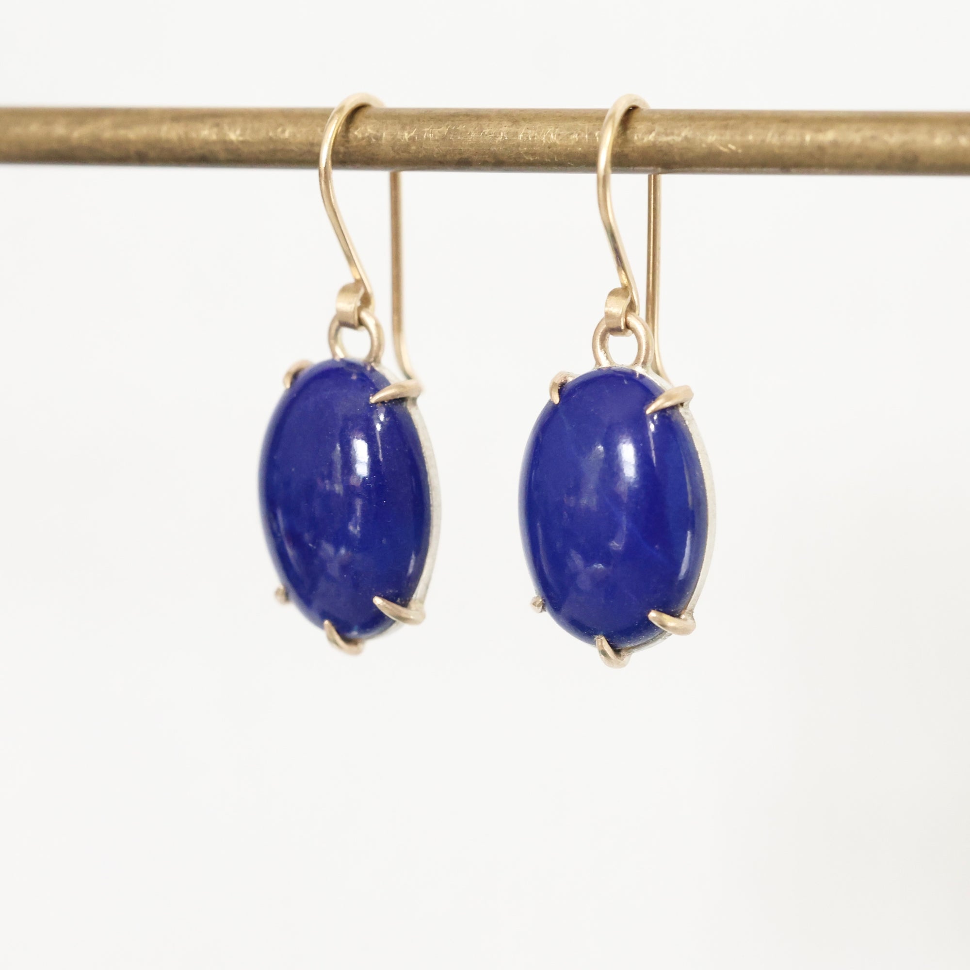 Pair of blue gemstone earrings on gold hooks against a white background