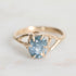 Gold ring with a blue gemstone on a light gray background