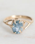 Gold ring with a blue gemstone on a light gray background