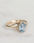 Gold ring with a blue gemstone on a light gray background