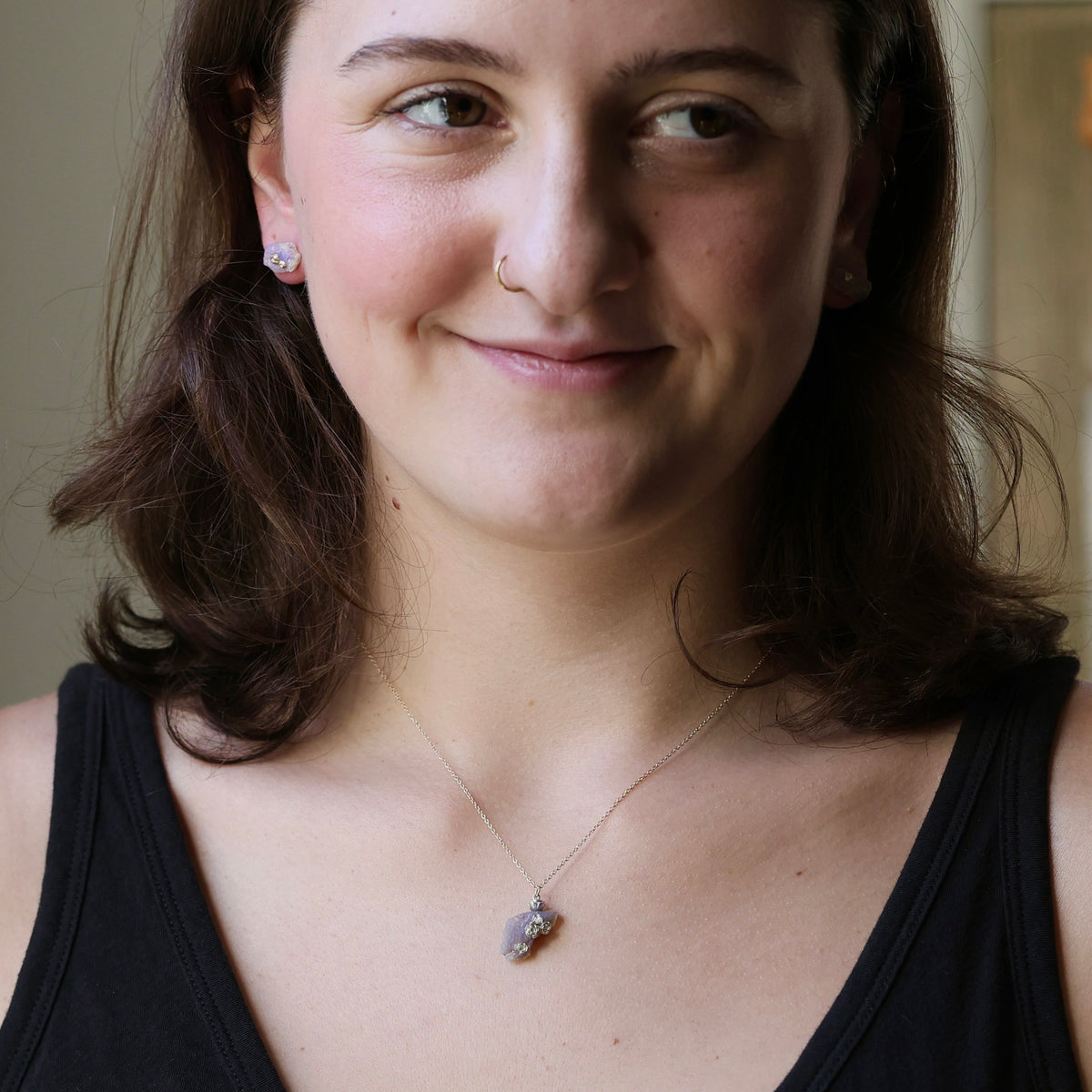 Woman wearing raw opal necklace with rose designs inside. 
