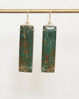Long jasper drop earrings with gold prongs hanging on a gold bar 