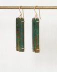 Pair of earrings with rectangular green stones on a white background