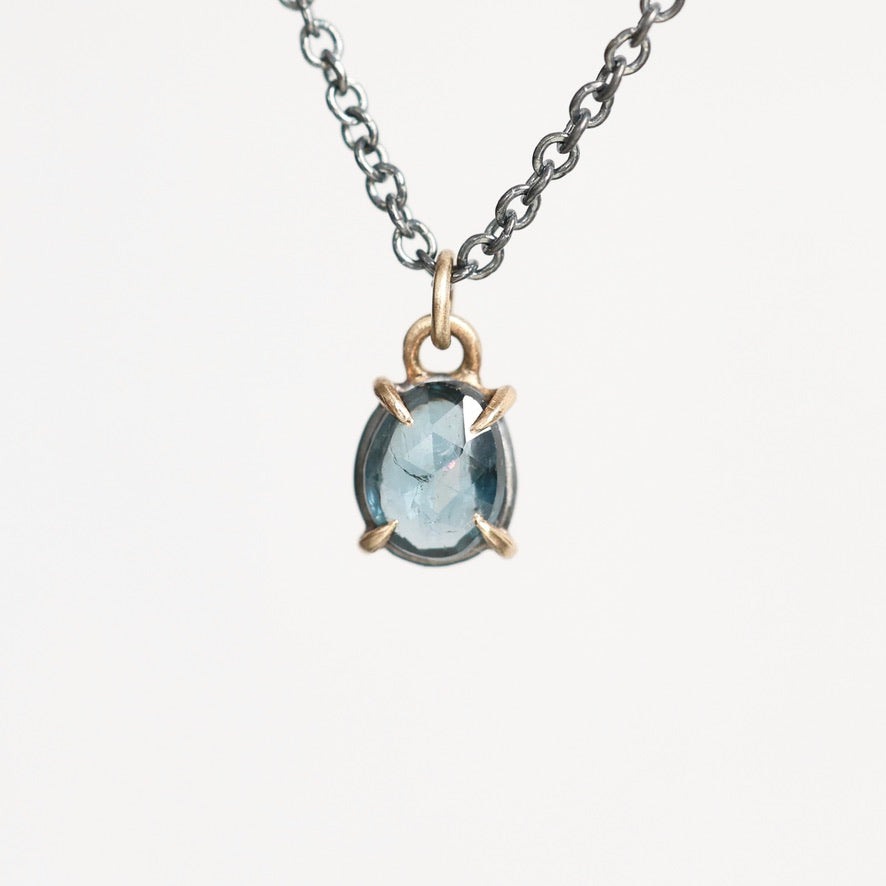 Blue stone pendant held in gold prongs