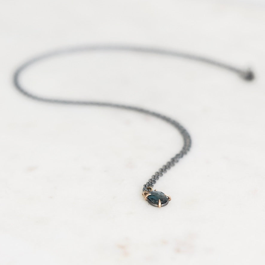 Blue stone pendant with oxidized chain on marble background
