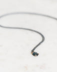 Blue stone pendant with oxidized chain on marble background
