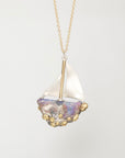 A delicate gold chain necklace featuring a unique sailboat pendant. The sailboat has a white fabric sail, a gold mast, and a hull made from iridescent mother-of-pearl with small gold seed beads along the bottom edge, set against a clean white background.