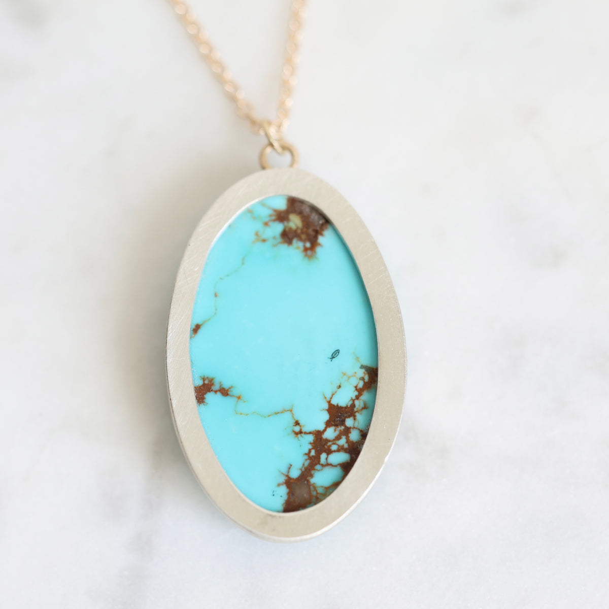 Back of necklace featuring a bezel set turquoise with natural veining and a small engraved fish