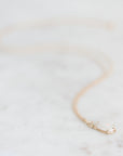 Opal necklace held in gold prongs with a gold chain laying on a marble background. 