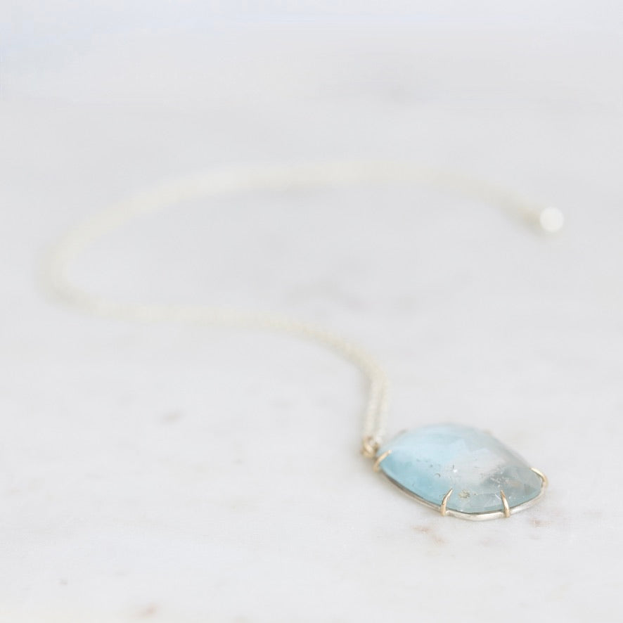Blue topaz necklace laying on white marble 