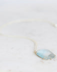Blue topaz necklace laying on white marble 