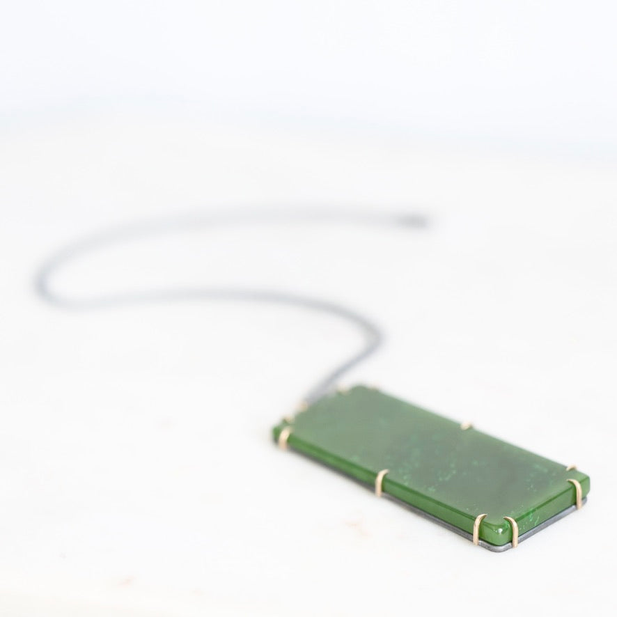 Large jade necklace pendant laying on surface