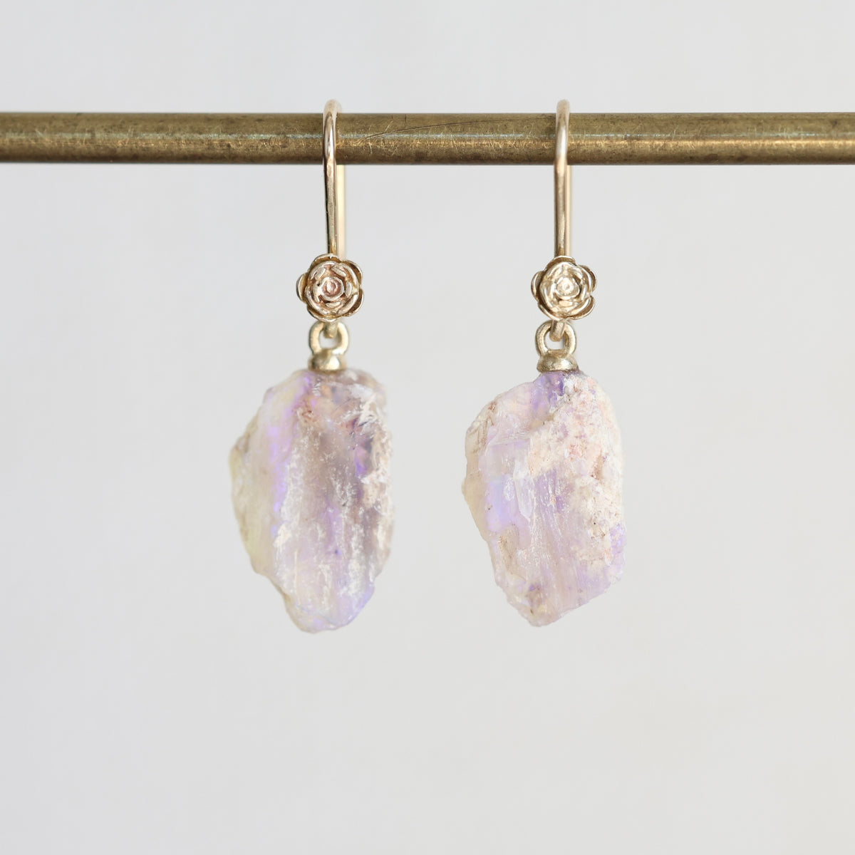 Pale colored fossilized opals suspended from gold ear wires with rose detailing. 