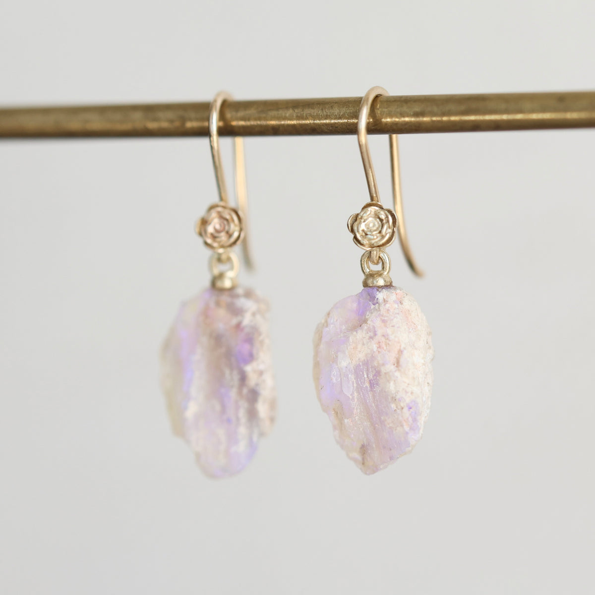Pale colored fossilized opals suspended from gold ear wires with rose detailing. 