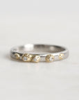 Silver ring with gold accents and small stones on a light gray background