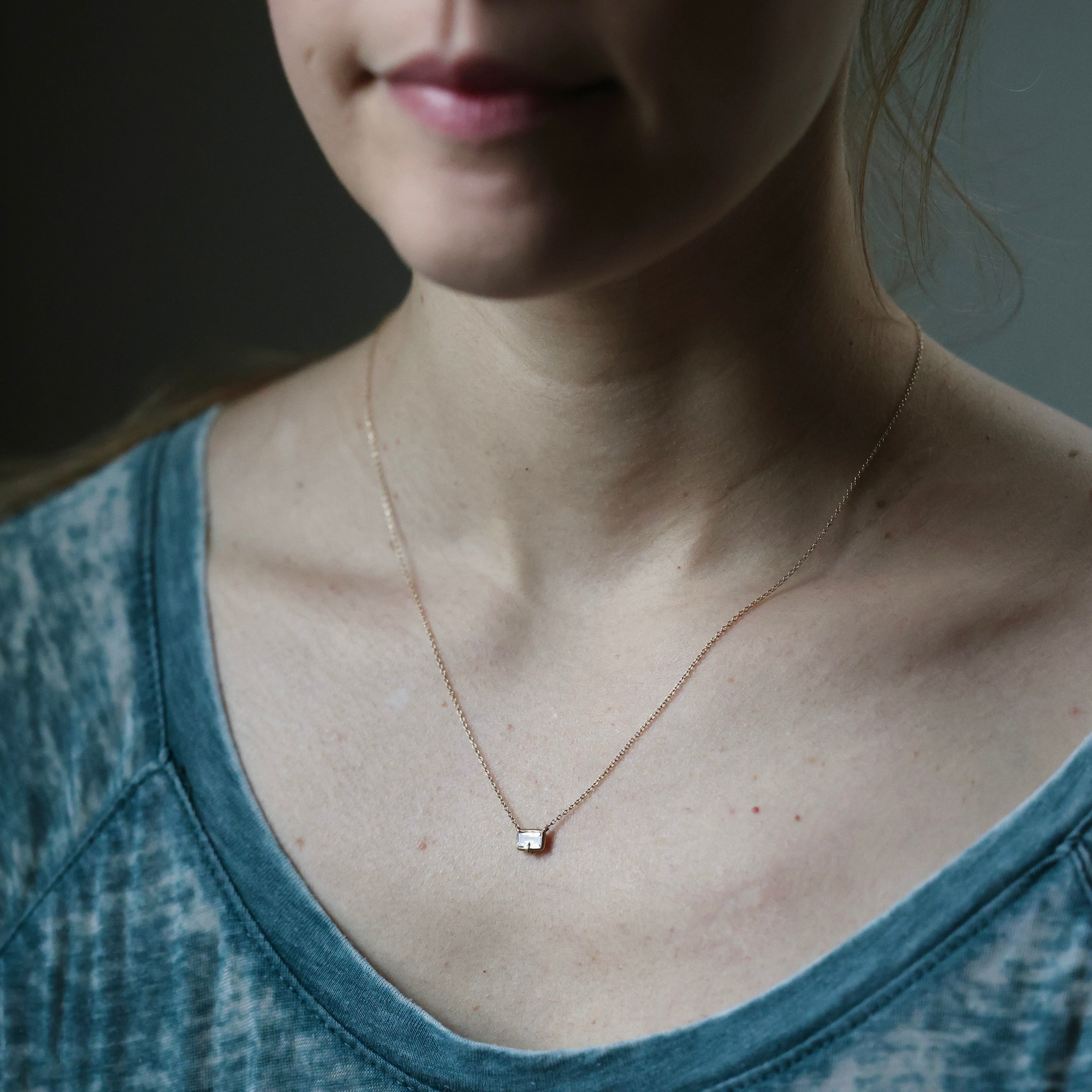 Close-up of a person wearing a delicate necklace with a small pendant.