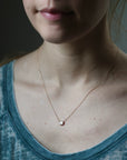 Close-up of a person wearing a delicate necklace with a small pendant.