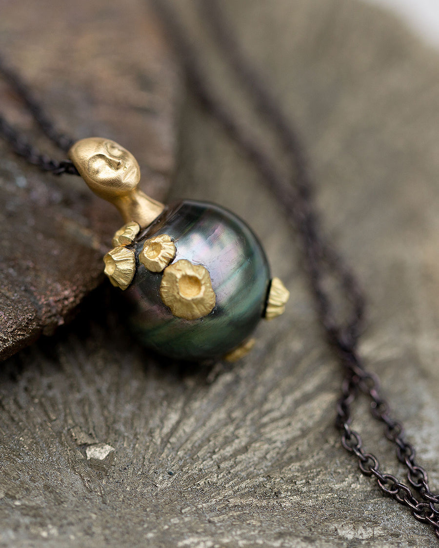 tahitian pearl pendant necklace by Hannah Blount. pearl has multiple gold barnacles and is topped with a gold grey lady cameo head. 