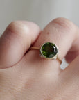 Video of 14k yellow gold bezel set ring with a green Tourmaline and bright sterling silver barnacles against a neutral background, displayed on ring finger.
