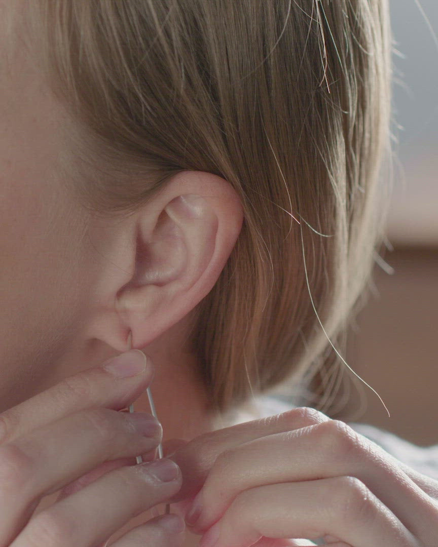 silver facet hoops being put on a person
